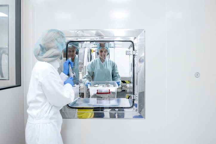 Female employees in a pharmaceutical industry seen while one is taking over the box with blister packs from the other just after manufacturing process
